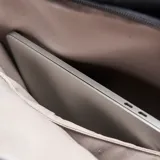 Mochila urbana de diseño minimalista en color negro, confeccionada en material textil resistente. Cuenta con un compartimento principal con cierre, un bolsillo frontal con solapa y cierre de hebilla metálica, y un asa superior reforzada.