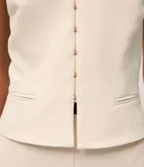 Blusa sastrera color marfil de corte halter con escote en V, cierre frontal con ganchos y bolsillos ribeteados simulados.