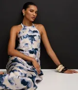 Vestido largo estilo slip con cuello halter que se ata en la nuca, sin mangas, con estampado abstracto en tonos azul y blanco que simula un efecto tie-dye.