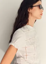 Camiseta blanca de algodón con diseño calado geométrico, corte recto y mangas cortas.
