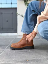 Botas cortas de cuero color marrón con elástico en los laterales y detalle de cuero texturizado en la parte delantera.