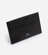 Tarjetero de poliuretano color negro con textura símil cuero de avestruz, múltiples compartimentos para tarjetas y aplique metálico con el logo de la marca en el frente.