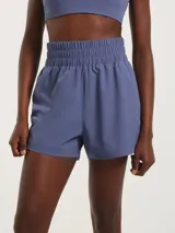 Short deportivo tipo runner de tiro alto con cintura elástica ancha. Presenta un diseño liso con aberturas laterales en el ruedo.