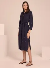 Vestido camisero midi color azul marino con estampado de lunares blancos, cuello camisero, mangas 3/4 y cinturón de lazo.