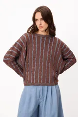 Sweater de punto con diseño de rayas verticales en tonos marrón y azul piedra, con textura de trenzas. Presenta cuello redondo, mangas largas con caída holgada y corte cropped.