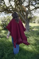 Ruana de tejido con textura color mostaza, con diseño amplio y fluido. Presenta volados aplicados en el cuello y las mangas, terminaciones con volados de lino y flecos en el ruedo. Incluye un lazo frontal regulable.