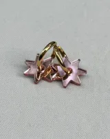 Aros tipo argolla dorada con dije colgante en forma de estrella de acrílico color rosa.