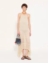 Vestido largo color beige, tejido en hilo fino con sutil brillo metálico. Diseño ajustado al cuerpo y con transparencia.
