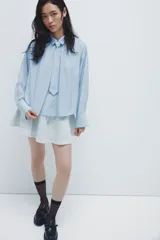 Camisa de manga larga con estampado de rayas verticales, cuello clásico y botonadura frontal. Incluye una corbata extraíble a juego con tira elástica. Presenta puños con abertura y botón, canesú con pliegue en la espalda y bajo recto con aberturas laterales redondeadas.