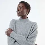 Sweater de punto acanalado en color gris, con cuello alto y mangas largas con diseño ligeramente abullonado.