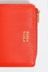 Billetera plateada de piel con textura tipo escamas, cierre de cremallera y logo metálico de la marca Bimba y Lola.