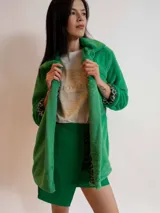 Tapado negro de piel sintética con cuello solapa y mangas largas. El forro interior de las mangas tiene un estampado animal print.