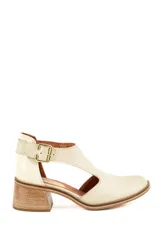 Sandalia de cuero color beige, con diseño cerrado en la puntera y el talón, aberturas laterales y tira con hebilla metálica dorada en el tobillo. Cuenta con taco bloque de madera.