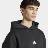 Canguro Adidas con capucha, color negro, con diseño de tres tiras blancas en ángulo en las mangas y logo de la marca en el centro del pecho. Cuenta con bolsillo frontal tipo canguro y puños acanalados.