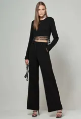 Blusa cropped negra de manga larga con cuello redondo y detalle de bordado metálico en el dobladillo inferior.