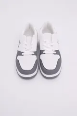 Zapatillas de diseño urbano en color blanco con inserciones en gris oscuro, cordones al tono y detalle de estrella bordada en el lateral.