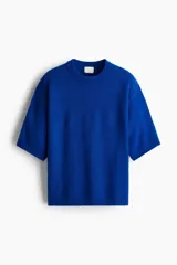 Remera de punto azul eléctrico de corte holgado, con cuello redondo, hombros caídos y mangas cortas hasta el codo. Presenta terminaciones acanaladas en el cuello, puños y ruedo.