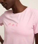 Remera deportiva rosada de microfibra perforada, con cuello redondo, manga corta, estampado pequeño en el pecho y bajo redondeado.