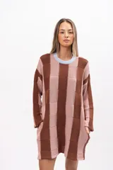 Buzo tipo poncho de corte oversize, con diseño de bloques verticales en tonos marrón y rosado. Presenta cuello redondo en color celeste, mangas largas y bolsillos laterales integrados.