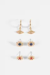 Set de tres pares de caravanas en tono dorado. Incluye un par de argollas con dije de ojo, un par de aros tipo sol con piedra central azul y un par de aros tipo flor con piedra central roja.