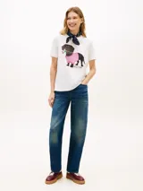 Remera blanca de manga corta y cuello redondo, con estampa en el pecho de un perro salchicha con buzo cuadrillé rosa y flores en la boca.