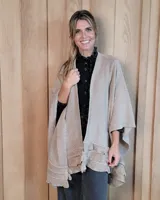 Ruana tejida en algodón, de color beige, con diseño abierto y detalle de volados en el ruedo.