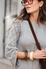 Vestido midi de tejido de punto color gris, con cuello a la base, mangas tres cuartos tipo oxford y detalle de calado geométrico en las mangas y en el ruedo.