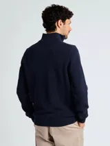 Sweater de punto color verde oscuro, con cuello alto y cierre frontal parcial, de manga larga y puños acanalados.