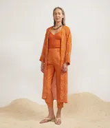 Kimono largo color naranja con estampado de rayas blancas diagonales, mangas largas y lazo para atar en la cintura.