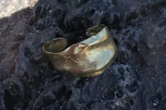 Brazalete rígido plateado con textura irregular.