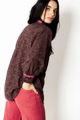 Camisa de broderie color chocolate con detalles de bies en color fucsia en el cuello, bolsillos y puños. Presenta un corte amplio, estilo relajado, mangas largas y cierre frontal con botones.