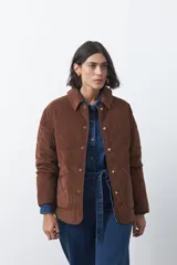 Campera capitoneada de algodón con diseño matelaseado, cuello camisero y cierre frontal con botones a presión. Presenta un corte relajado y bolsillos frontales.