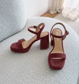 Sandalias de cuero color uva, con taco ancho, plataforma delantera y tira en el tobillo con hebilla ajustable.