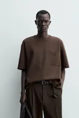 Remera de corte relajado confeccionada en tejido compacto de mezcla de algodón con elasticidad. Presenta cuello redondo, manga corta y un bolsillo frontal de plastrón.