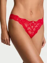 Bombacha tipo thong de encaje rojo, de tiro bajo, con detalle de roseta frontal.