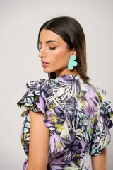 Vestido largo con estampado floral en tonos lila, verde y negro. Tiene escote en V, mangas cortas con volados y corte cruzado con lazo en la cintura.
