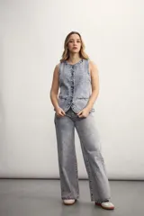 Chaleco azul de denim con cuello en V y cierre frontal con botones metálicos. Posee bolsillos delanteros y corte clásico.