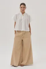 Blusa blanca de algodón con detalle metalizado, cuello con punto smock y mangas raglán.