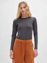 Camiseta negra de manga larga, con tejido acanalado, cuello redondo a la base y corte tipo crop. Presenta costuras rojas a la vista y un logo "M" bordado en rojo en el lateral izquierdo.