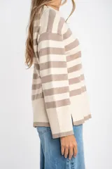 Sweater de punto con diseño a rayas horizontales en color negro y crema. Presenta cuello redondo, mangas largas con puños acanalados y un detalle de borde en tono bronce metalizado en el ruedo y los puños.