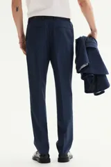 Pantalón de traje de corte ajustado, con cierre frontal y corchete oculto. Presenta bolsillos laterales, bolsillos traseros ribeteados y raya marcada en el frente.
