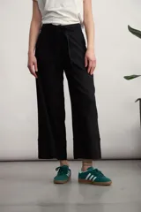 Pantalón negro de corte recto y tiro alto, con cintura elástica y lazo ajustable del mismo tejido. Presenta bolsillos laterales y un dobladillo ancho en la parte inferior.