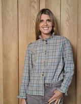 Camisa de manga larga con estampado de rayas verticales en tonos blanco y lila. Presenta cuello alto con volados, cierre frontal con doble botonadura y puños con volados.