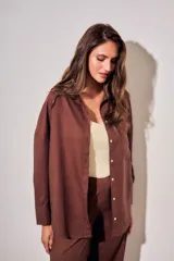 Camisa oversize color marrón, confeccionada en mezcla de viscosa y lino, con cuello clásico, cierre frontal con botones y un bolsillo aplicado en el pecho.