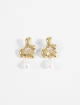 Aros colgantes con forma de flor irregular dorada, con centro calado y dije de perla colgante.