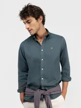 Camisa de hombre de corte regular fit, confeccionada en algodón con acabado vintage. Presenta cuello buttondown, cierre frontal con botones, mangas largas con puño simple y logo bordado en el pecho.