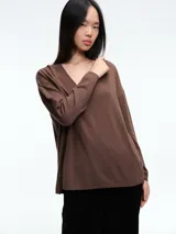 Sweater de escote en V profundo, confeccionado en tejido ligero con micro lentejuelas. Presenta hombros caídos, mangas largas y un calce relajado.