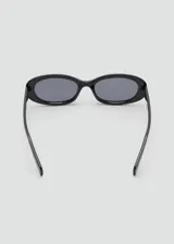 Lentes de sol con armazón de policarbonato negro y diseño de montura ovalada angosta estilo retro.