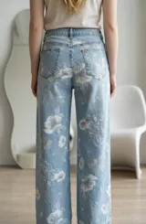 Jean de corte recto y tiro medio, confeccionado en denim celeste con estampado floral en tonos claros. Presenta cierre frontal con botón y bolsillos laterales y traseros.