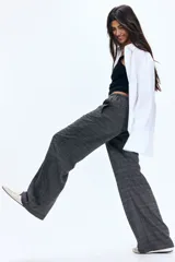 Pantalón holgado de pierna recta y tiro medio, confeccionado en tejido a cuadros gris. Presenta cintura elástica con cordón ajustable y bolsillos laterales.